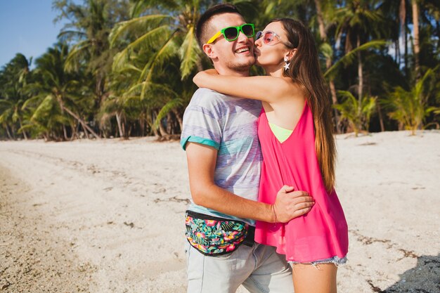 Hermosa joven pareja caminando en la playa tropical, tailandia, abrazándose, riendo, gafas de sol, divirtiéndose, atuendo hipster, estilo casual, luna de miel, vacaciones, verano, estado de ánimo soleado y romántico