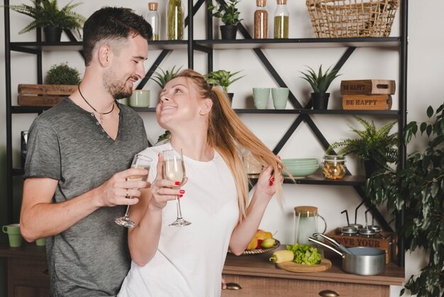 Hermosa joven pareja con champán flauta en la cocina