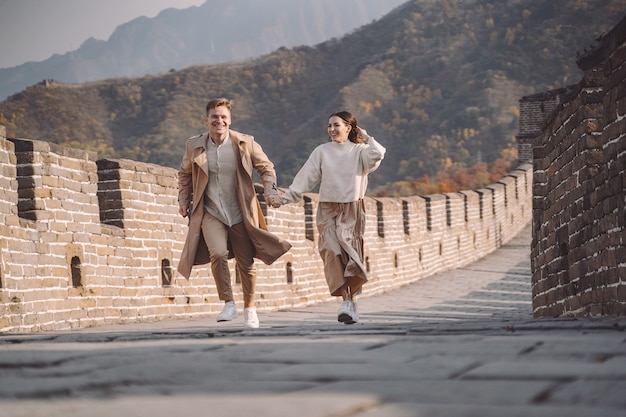 Hermosa joven pareja corriendo y saltando en la Gran Muralla de China.