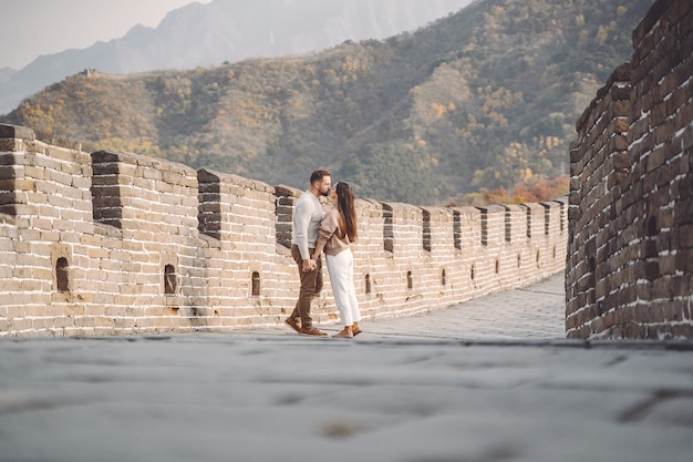 Hermosa joven pareja corriendo y saltando en la Gran Muralla de China.
