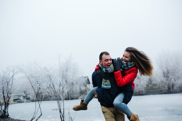 Hermosa joven pareja divirtiéndose en el parque cubierto de nieve