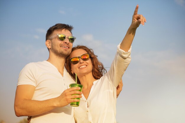 Hermosa joven pareja enamorada sonriendo hombre y mujer en gafas de sol mirando el cielo azul