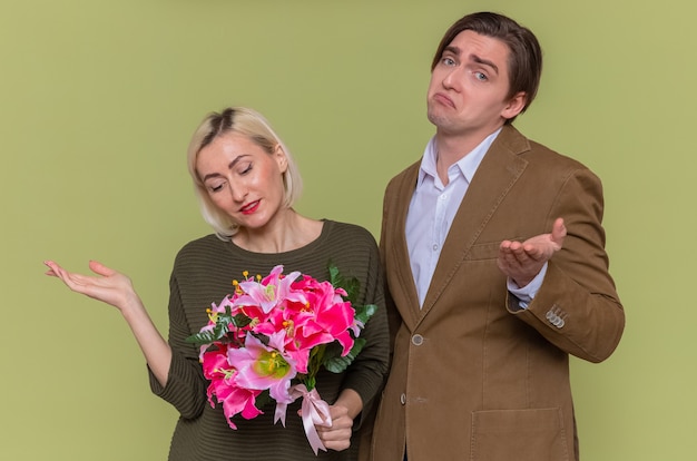 Hermosa joven pareja feliz hombre y mujer con ramo de flores