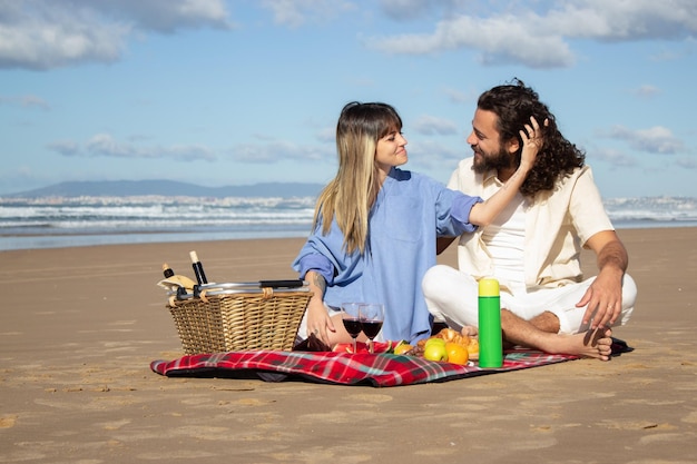 Hermosa joven pareja haciendo un picnic en la playa