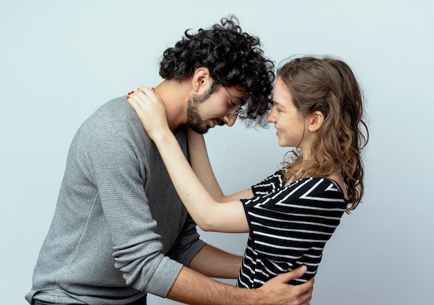 Hermosa joven pareja hombre y mujer felices enamorados abrazándose unos a otros sobre la pared blanca