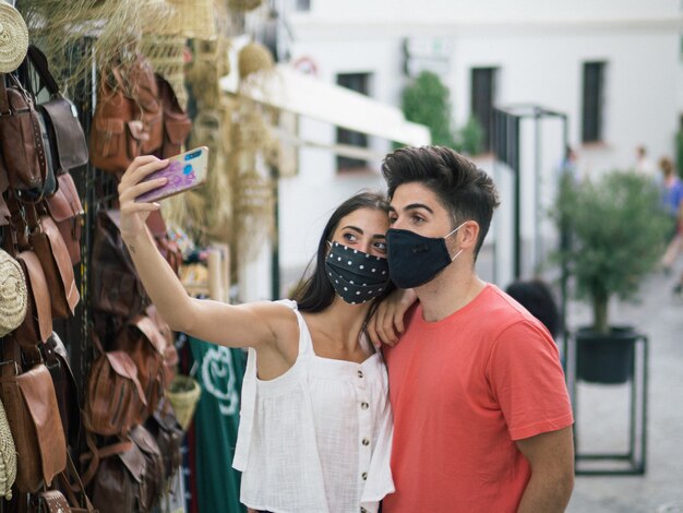 Hermosa joven pareja con máscaras médicas en una cita romántica: la nueva normalidad debido al Covid-19