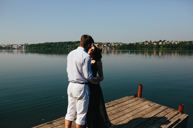 Hermosa joven pareja pasa tiempo en el muelle de madera en el lago