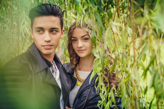 Hermosa joven pareja posando bajo un árbol verde. Día de San Valentín.