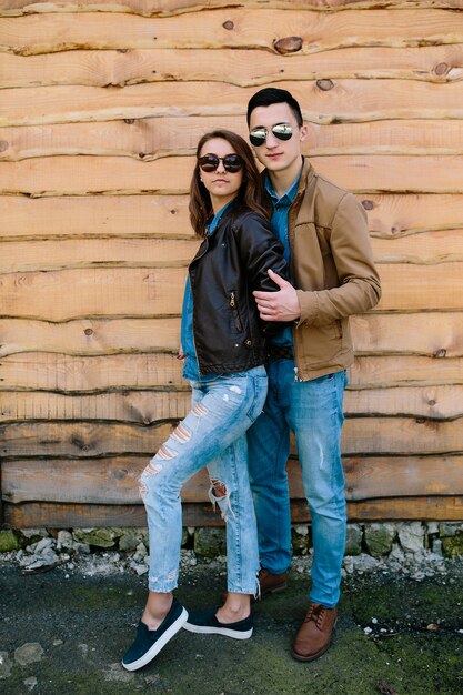 Hermosa joven pareja posando sobre pared de madera