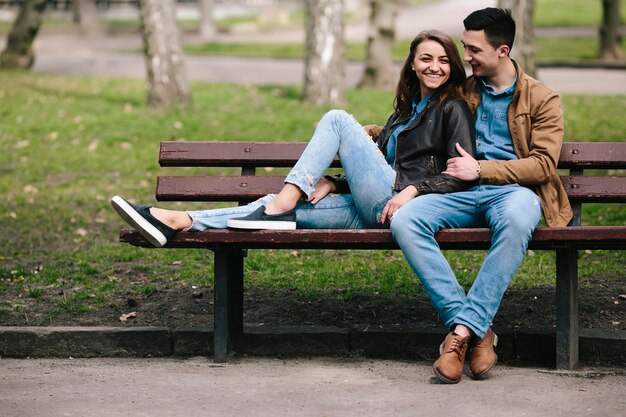 Hermosa joven pareja relajándose en un banco en el parque