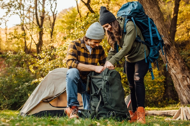 Hermosa joven pareja reúne sus mochilas en una caminata