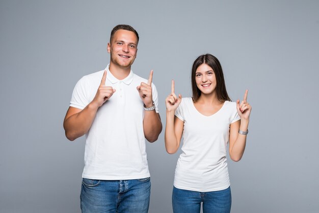 Hermosa joven pareja en ropa casual camiseta blanca y jeans levantando los dedos