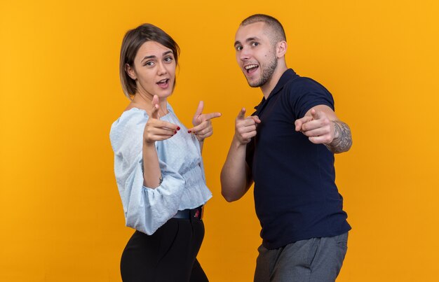 Hermosa joven pareja en ropa casual hombre y mujer feliz y positivo apuntando con los dedos índices sonriendo de pie