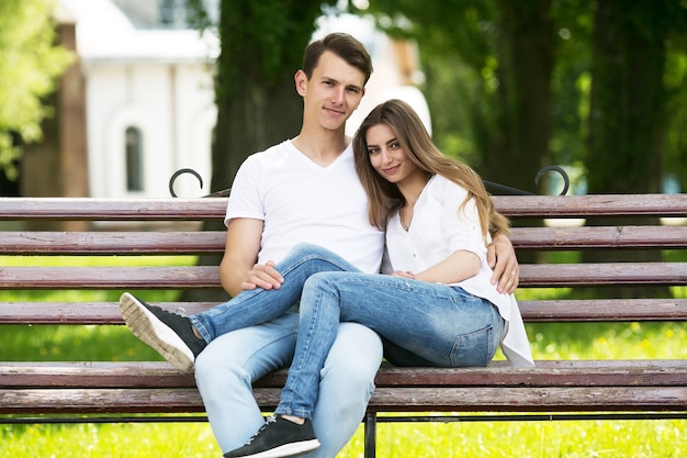 Hermosa joven pareja sentada en un banco en el parque
