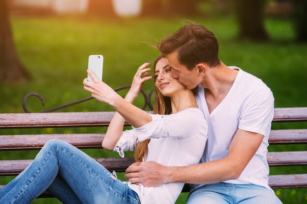 Hermosa joven pareja sentada en un banco en el parque