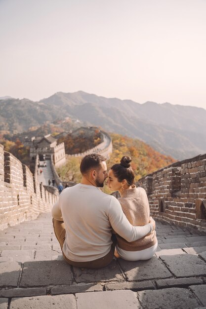 Hermosa joven pareja sentada y mostrando afecto en la Gran Muralla de China.