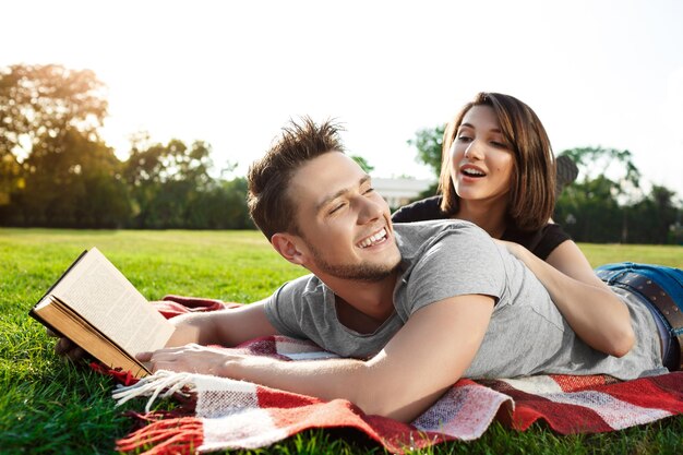 Hermosa joven pareja sonriendo, descansando, relajándose en un picnic en el parque.