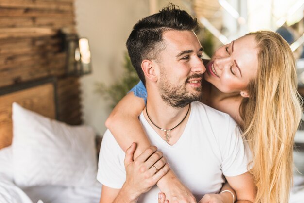 Hermosa joven pareja sonriendo mientras está sentado en el dormitorio