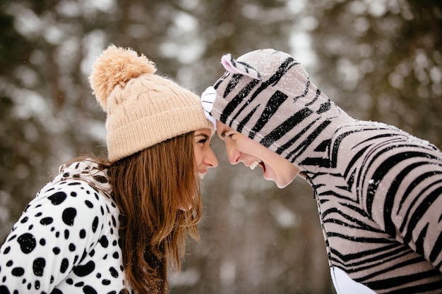 Hermosa joven pareja en trajes divertidos pasar tiempo de diversión en el invierno.