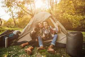 Foto gratuita hermosa joven pareja en vestido casual sentado en la carpa en el bosque