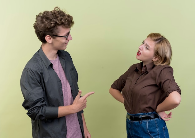 Foto gratuita hermosa joven pareja vistiendo ropa casual hombre y mujer peleando de pie sobre la pared de luz