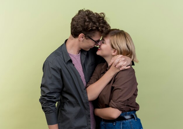 Hermosa joven pareja vistiendo ropa casual niño y niña feliz enamorado abrazándose sobre pared ligera