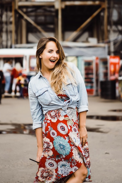 Una hermosa joven de pelo largo con un vaso de café sonríe y se ríe. retrato de primer plano afuera