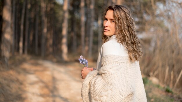 Hermosa joven con el pelo rizado sosteniendo una flor