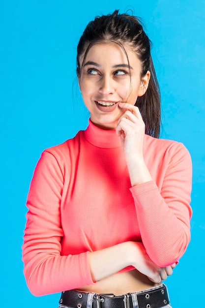 Hermosa joven de pie sobre fondo azul y pensando Foto de alta calidad