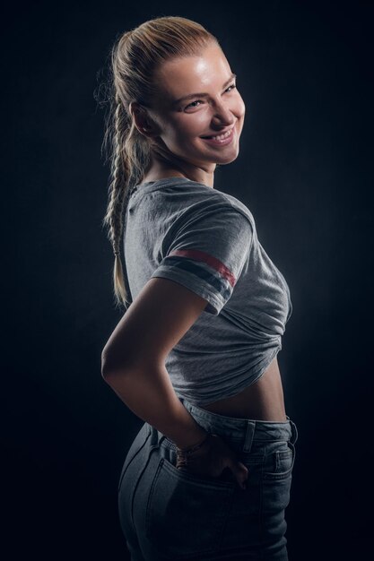 Hermosa joven posa para el fotógrafo en un estudio fotográfico oscuro.