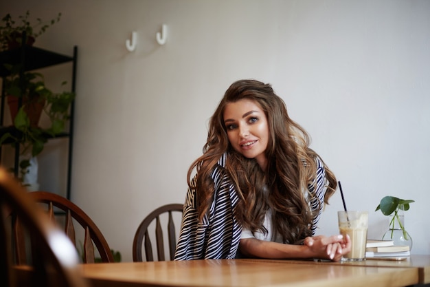 Foto gratuita una hermosa joven está posando en un café