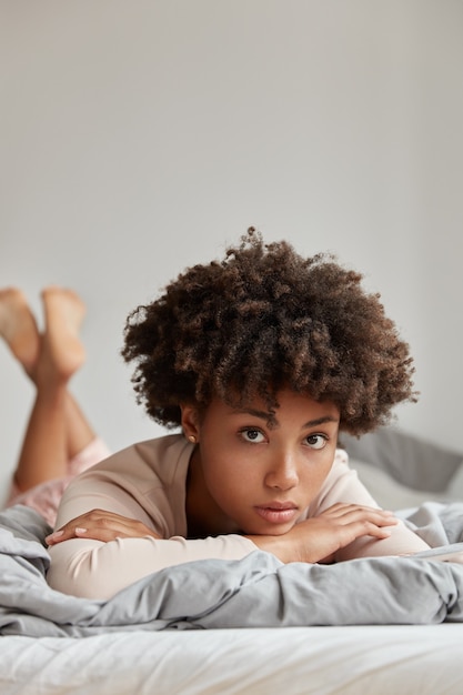 Hermosa joven posando en casa en una cama cómoda