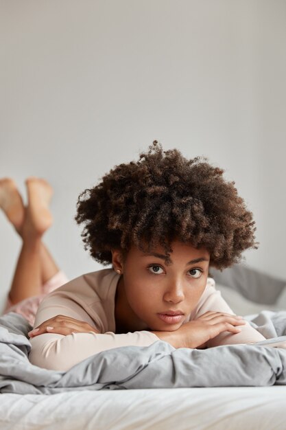 Hermosa joven posando en casa en una cama cómoda