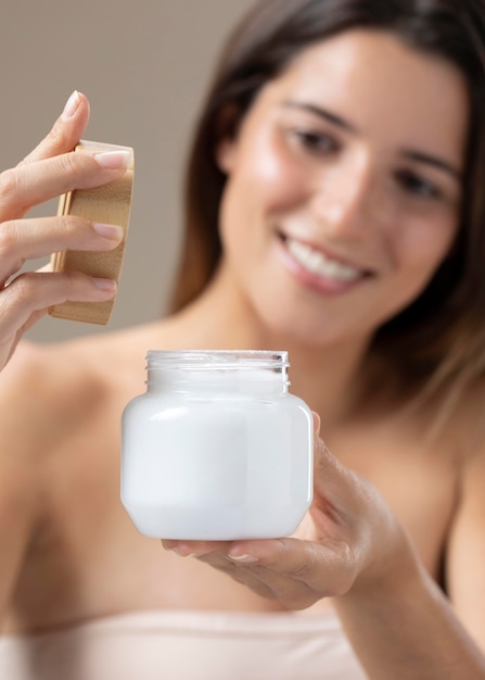 Hermosa joven posando con productos para el cuidado de la piel