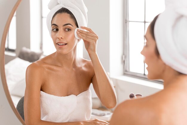 Hermosa joven con productos de spa en casa