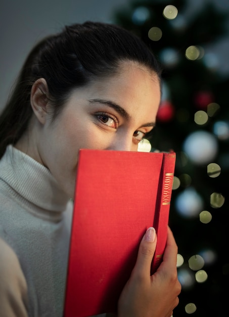 Foto gratuita hermosa joven que cubre la cara con el libro