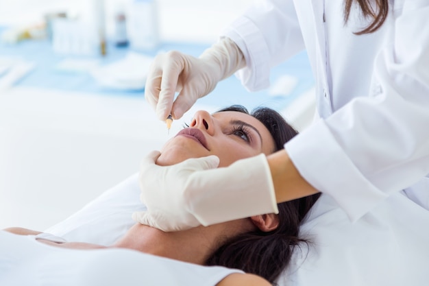 Hermosa joven recibiendo inyección cosmética de botox en su rostro.