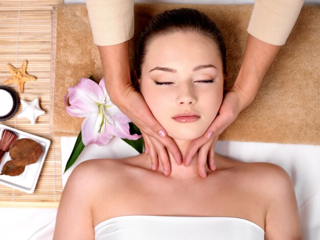 Hermosa joven recibiendo masaje para el cuello en el salón de spa