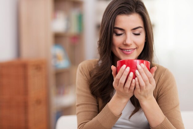 Hermosa joven relajante con una taza de café en casa