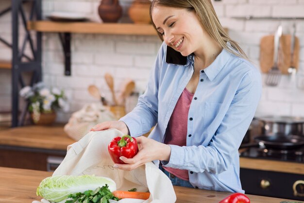 Hermosa joven sacando comestibles de la bolsa