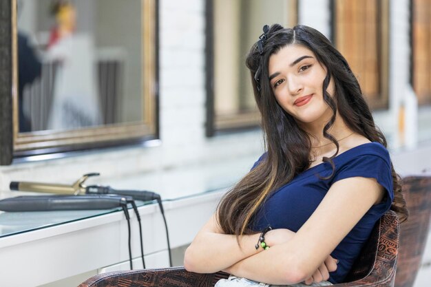 Una hermosa joven sentada en la barbería y mirando a la cámara Foto de alta calidad