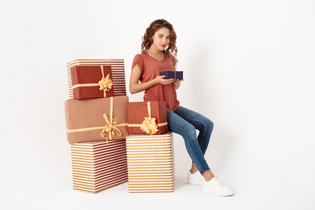 Foto gratuita hermosa joven sentada en una gran caja de regalo sosteniendo una más pequeña en las manos aislada