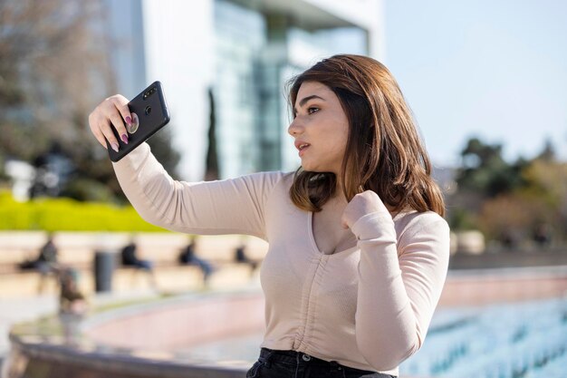 La hermosa joven sentada en el parque y tomando selfie Foto de alta calidad