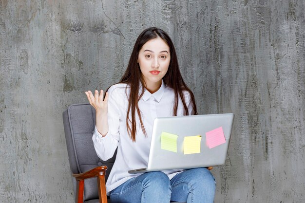 Hermosa joven sentada en un sillón con una laptop posando. foto de alta calidad