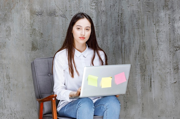 Hermosa joven sentada en un sillón con una llamada con una laptop. foto de alta calidad