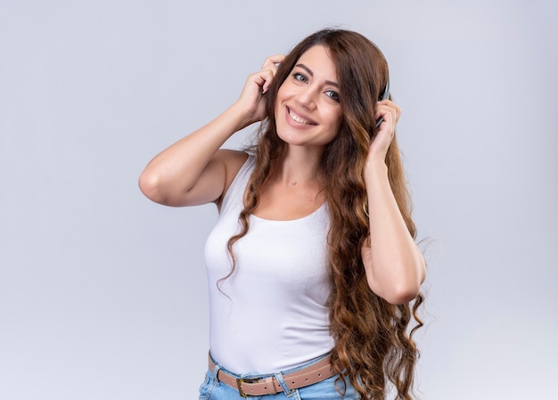 Foto gratuita hermosa joven sonriente con auriculares poniendo las manos sobre ellos