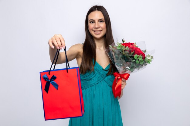 Hermosa joven sonriente en feliz día de San Valentín con ramo de flores con bolsa de regalo