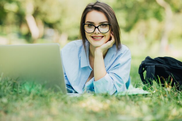 Hermosa joven sonriente con laptop en Citypark en día soleado