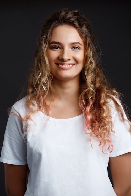 Hermosa joven sonriente sobre la pared gris.