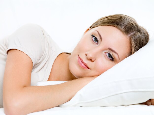 Hermosa joven sonriente tiene un descanso en la cama